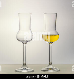 Zwei Grappa Gläser gefüllt eins leer stehend nebeneinander Stockfoto