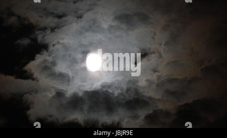 Vollmond hinter Wolken in der Nacht. schwarzem Hintergrund Stockfoto