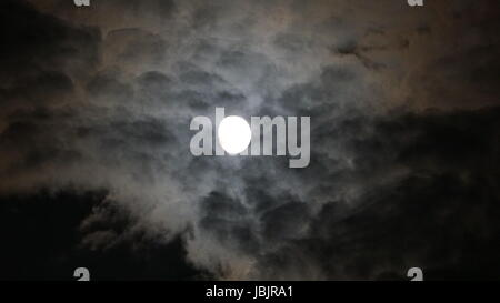 Vollmond hinter Wolken in der Nacht. schwarzem Hintergrund Stockfoto