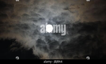 Vollmond hinter Wolken in der Nacht. schwarzem Hintergrund Stockfoto