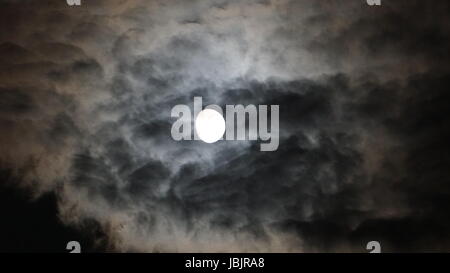 Vollmond hinter Wolken in der Nacht. schwarzem Hintergrund Stockfoto