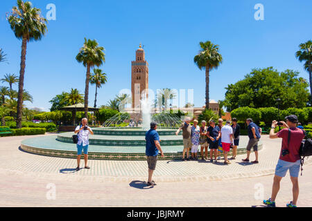 Marrakesch, Marokko - 12. Mai 2017: Eine Gruppe von Touristen fotografieren von einander vor dem Brunnen in Koutoubia Gärten mit der Koutoubia Stockfoto