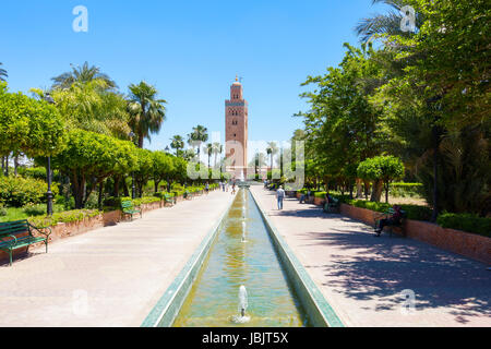 Marrakesch, Marokko - 12. Mai 2017: Touristen und Einheimische sind entspannend in der Koutoubia Gärten an einem sonnigen Tag mit der Koutoubia-Moschee in der Zeitmessung Stockfoto