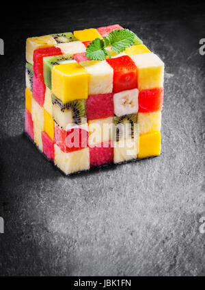 Bunte Gourmet-Würfel aus gewürfelten frischen tropischen Früchten mit Wassermelone, Melone, Orange, Erdbeere, Banane, Kiwi und Apfel garniert mit Minze auf einer Schiefertafel Küchentisch mit Exemplar Stockfoto