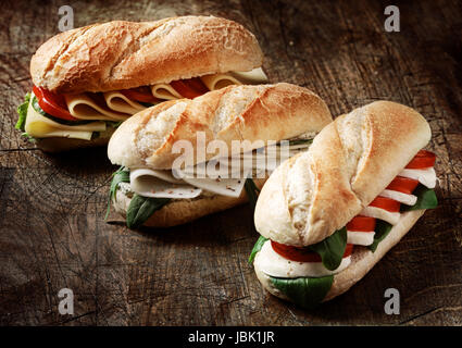 Frisch gebackene knusprige golden vegetarische Baguette in einer Bäckerei mit einer Vielzahl von Käse, Kräuter und Salat Füllungen auf einem rustikalen Holz Hintergrund, Nahaufnahme Stockfoto