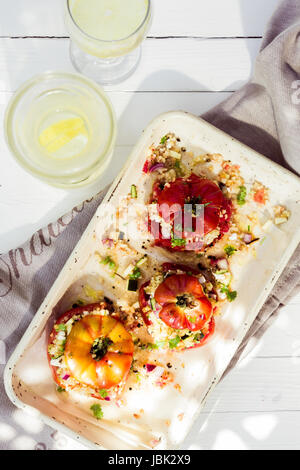 Gefüllte Reife frische Tomaten mit Getreide, Reis, Zwiebeln und Kräutern bis zum Überlaufen gefüllt und auf einem Teller serviert Stockfoto