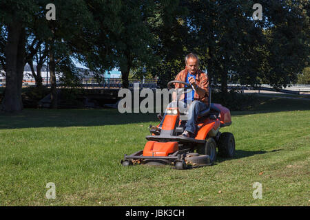 Mann fahren einen Rasenmäher im Stadtpark Stockfoto