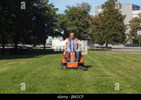 Mann fahren einen Rasenmäher im Stadtpark Stockfoto