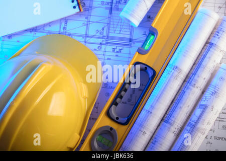 Brötchen mit Bauprojekten, Ausrüstung von Architekt: Sturzhelm und Wasserwaage auf Holztisch. Stockfoto