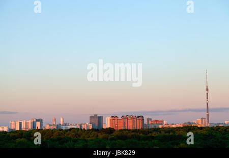 Rosa Sonnenuntergang in blauem Himmel über den städtischen Häusern und Fernsehturm im Frühjahr Stockfoto