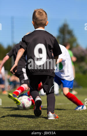 Kinder spielen Fußball im Freien an einem sonnigen Tag. Marken sind entfernt worden. Stockfoto