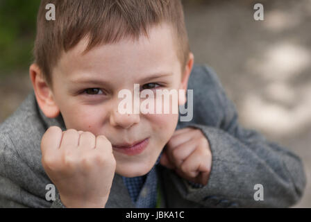 Kleinen lächelnden jungen droht mit Fäusten unter Boxen rack Stockfoto