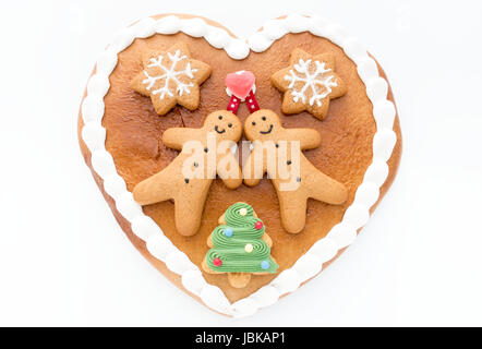 Nahaufnahme von einer süßen Lebkuchenherz verziert mit Lebkuchenmänner, Lebkuchen-Sterne und einem Weihnachtsbaum Cookie auf weißem Hintergrund. Stockfoto