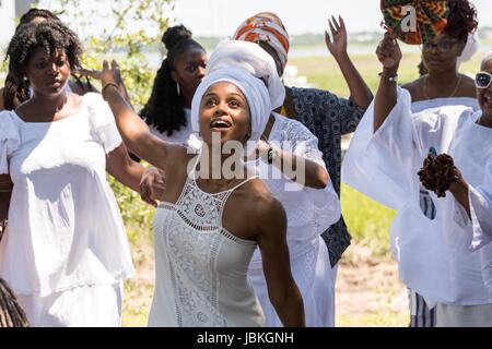 Nachkommen der versklavten Afrikanern brachte nach Charleston im Middle Passage Tanz zu Ehren ihrer Angehörigen verloren, während eine Gedenkveranstaltung entlang dem Salzwasser Marsh 10. Juni 2017 in Sullivans Island, South Carolina. Die Middle Passage bezieht sich auf den Dreieckshandel in dem Millionen von Afrikanern als Teil des Atlantischen Sklavenhandels in die neue Welt verschifft wurden. Schätzungsweise 15 % der Afrikaner starben in den Prozess der Erfassung und den Transport auf See und erheblich mehr. Die Gesamtzahl der afrikanischen Todesfälle, die direkt auf die Middle Passage-Reise wird auf bis zu 2 Millionen geschätzt. Stockfoto