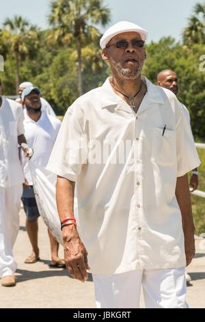 Rundfunk-Moderator der Show Roots Musik Karamu, Osei Chandler, führt Nachkommen der versklavten Afrikanern brachte nach Charleston in der Middle Passage in einer Prozession während einer Gedenkveranstaltung am Fort Moutrie National Monument 10. Juni 2017 in Sullivans Island, South Carolina. Die Middle Passage bezieht sich auf den Dreieckshandel in dem Millionen von Afrikanern als Teil des Atlantischen Sklavenhandels in die neue Welt verschifft wurden. Schätzungsweise 15 % der Afrikaner starben in den Prozess der Erfassung und den Transport auf See und erheblich mehr. Stockfoto