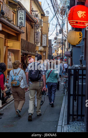Masse der europäischen und asiatischen Touristen zu Fuß durch eine schmale Straße, am frühen Abend Gion, Kyoto. Stockfoto