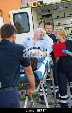 Paramedizinische Team helfen Verletzten senior Mann liegend auf Bahre im freien Stockfoto