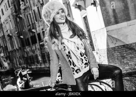 Venedig. Abseits der ausgetretenen Pfade. lächelnde trendige Frau in Pelzmütze in Venedig im Winter Blick in die Ferne Stockfoto