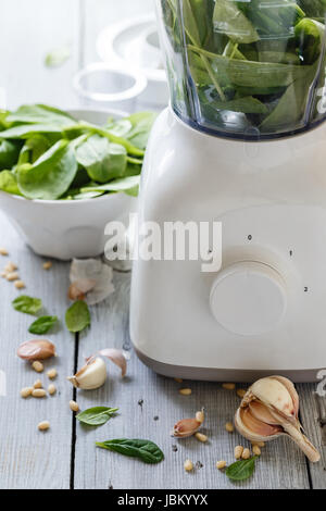 Spinat-Pesto: Blattspinat, Knoblauch und Pinienkerne auf weißem Holz Hintergrund Stockfoto