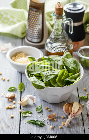 Spinat-Pesto: Blattspinat, Knoblauch, Pinienkernen, Olivenöl und Käse auf weißem Holz Hintergrund Stockfoto