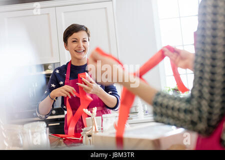 Lächelnd weibliche Caterer Verpackung Backwaren in Kartons mit rotem Band in Küche Stockfoto