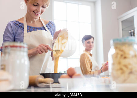 Weibliche Caterer backen, Gießen Kuchenteig in Zinn in Küche Stockfoto