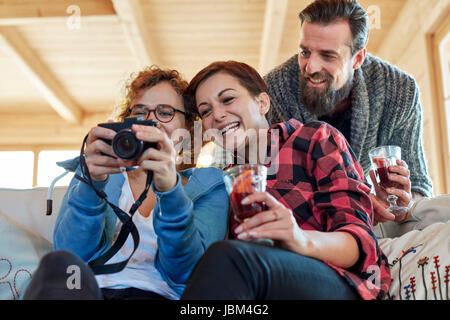 Blick auf Fotos auf Digitalkamera und trinken Freunde hot Toddy in Kabine Stockfoto