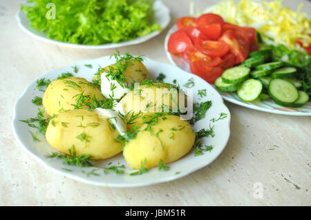 Frisches Bio-Gemüse und gekochten neuen Kartoffeln auf den Tellern auf dem Holztisch. Großaufnahme, selektiven Fokus. Stockfoto