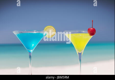 Blaue und gelbe Cocktails in der Martini-Gläser am tropischen Strand Stockfoto