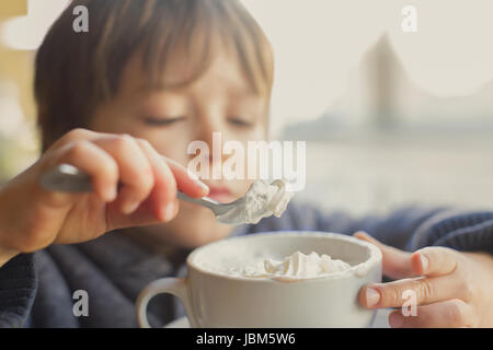 Nahaufnahme junge schöpfen und Schlagsahne aus heißer Kakao essen Stockfoto