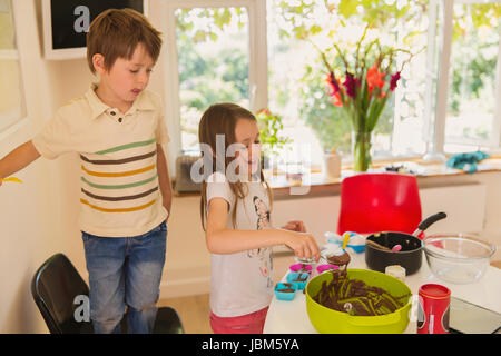 Jungen und Mädchen Bruder und Schwester machen Schokoladen Cupcakes in Küche Stockfoto