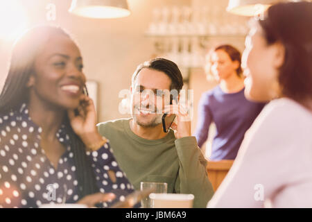 Menschen reden über Handy hinter Freundinnen reden in der Bar Stockfoto