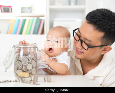 Asiatische Familie Lifestyle zu Hause. Vater und Kind, die Münzen auf Geld Glas, finanzielle Planungskonzept zu speichern. Stockfoto