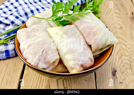 Vorbereitete Kohlrouladen mit Hackfleisch, Petersilie in eine Schüssel, Serviette auf dem Hintergrund der Holzbretter Stockfoto