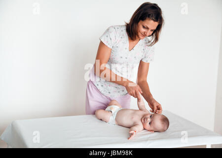 Frau Doktor macht dem Baby eine sanfte Massage. Die Kindermassage. Stockfoto