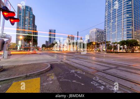 Eine Straßenansicht von Downtown San Diego, Kalifornien, USA, in der Dämmerung. Eine Nacht Blick auf Transport, Citylights und Wolkenkratzer und lokalen Gebäude in der Marina am Wasser. Stockfoto