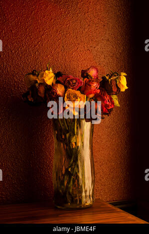 Bunte Rosen in Glasvase mit warmen Fenster Fensterlicht welke Stockfoto