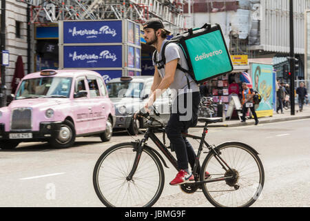 Ein Deliveroo-Radfahrer auf seinem Fahrrad im Verkehr auf der Tottenham Court Road, im Zentrum von London, England, Großbritannien Stockfoto