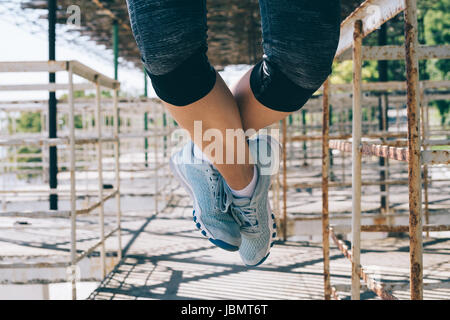 Sportliche junge Frau tun Klimmzüge in den Morgen im Freien, Nahaufnahme. Weibliche Beine in blauen Turnschuhen. Stockfoto