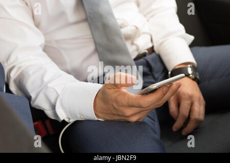Nahaufnahme eines Geschäftsmannes mit Smartphone während der Fahrt auf dem Rücksitz eines Autos. Fokus auf mobile Geräte. Stockfoto