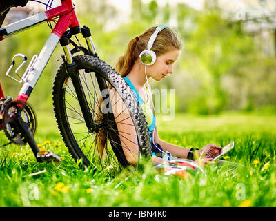 Fahrräder Radsport Mädchen. Mädchen fährt Rad. Mädchen tragen Kopfhörer im Radsport Uhr in Tablet pc in der Nähe von Fahrrad. Radfahrer auf der Suche nach pc Tablet und Auflisten von Musik. Stockfoto