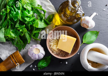 Selbstgemachtem Pesto Zutaten: Basilikum, Olivenöl, Knoblauch und Käse auf schwarzem Schiefer Stein Stockfoto