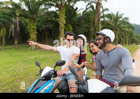 Zwei paar Smart auf Motorrad, junger Mann und Frau mit Zelle Telefon Reise mit Fahrrad auf Tropical Forest Road Stockfoto