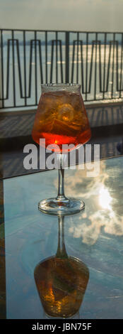 Kellner vorbereitet Aperol Sprits Sommer cocktail mit Aperol, prosecco, Eis-Würfel und Orange im Weinglas, bereit, auf der sonnigen Terrasse mit Meer zu trinken Stockfoto