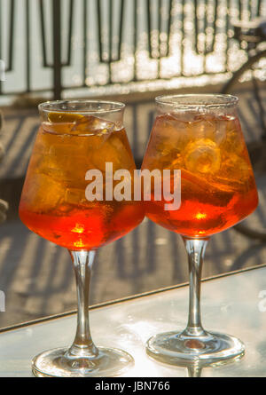 Kellner vorbereitet Aperol Sprits Sommer cocktail mit Aperol, prosecco, Eis-Würfel und Orange im Weinglas, bereit, auf der sonnigen Terrasse mit Meer zu trinken Stockfoto