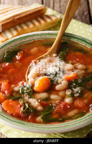 Frische heiße Bohnensuppe mit Tomaten, Spinat, Karotten und Parmesan Nahaufnahme in einen Teller. Vertikal Stockfoto