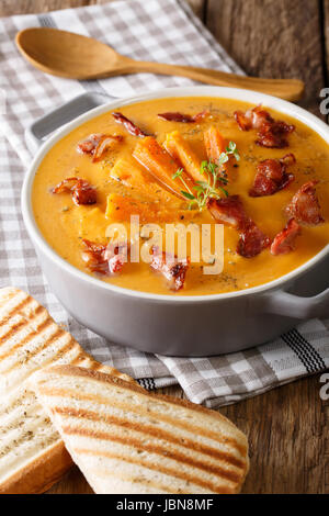 Gesunde süsse Kartoffel Creme Suppe mit Speck und Kräuter in einen Topf geben und Toast Nahaufnahme auf einem Tisch. Vertikal Stockfoto