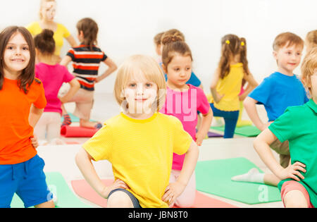 Große Gruppe von glückliche Kinder kniend mit ihren Händen auf Taille, während der Gymnastik im Sportverein Stockfoto