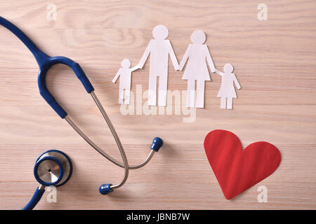 Konzept der Familienmedizin mit Ostetoscope und Papier Ausschnitt der Familie und roten Herzen auf einem Holztisch. Ansicht von oben. Horizontale Komposition. Stockfoto