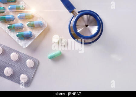 Konzept der verschreibungspflichtigen Medikamente von einem Arzt. Stethoskop und Medizin Tabletten auf einem weißen Tisch mit glänzend. Ansicht von oben. Horizontale Komposition. Stockfoto